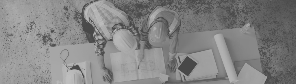 Deux professionnels casqués consultant des plans de chantier